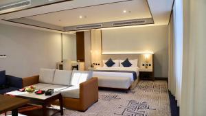 Five Seasons Hotel في تبوك: غرفه فندقيه بسرير واريكه