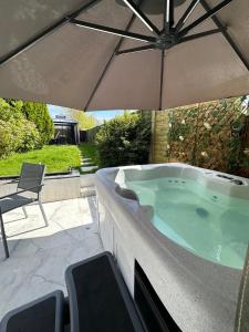 博爾頓的住宿－Entire Luxury House big garden+Hot tub+BBQ+access to forest & river，庭院内带遮阳伞的热水浴池