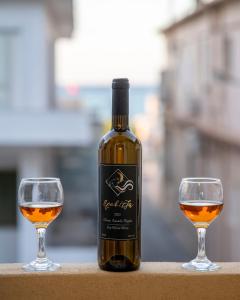 Upper Samitos Rooms في Áyios Andónios: زجاجة من النبيذ بجوار كأسين من النبيذ
