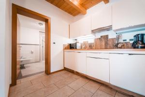 a kitchen with white cabinets and a tile floor at ALMRESIDENZ UNTERRAIN - with FREE SKI BUS SHUTTLE in Valdaora +186 photos
