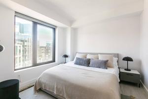 1 dormitorio blanco con 1 cama grande y 2 ventanas en 1+Den/1 Luxury apartment in Seaport en Boston