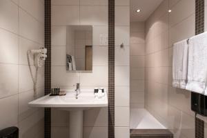 a white bathroom with a sink and a shower at Van der Valk Waterloo in Waterloo