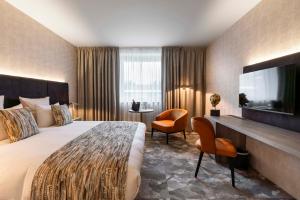 um quarto de hotel com uma cama e uma televisão de ecrã plano em Van der Valk Waterloo em Waterloo