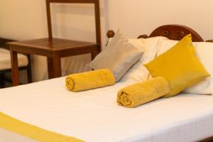 Una cama con dos almohadas amarillas encima. en Xotic Resort Upper Floor, en Kurunegala
