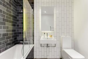 a bathroom with a sink and a toilet and a tub at Khayat Homes - The Khalifa - One Bed Luxury APt in London