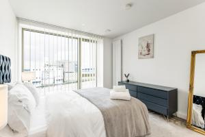 a white bedroom with a bed and a mirror at Khayat Homes - The Khalifa - One Bed Luxury APt in London
