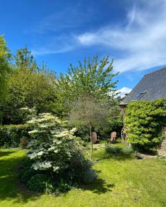 a garden with a tree with white flowers and a house at Une nuit chez une artisane in Josselin