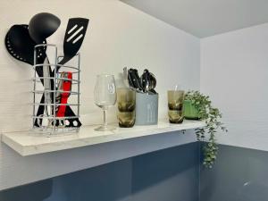 a shelf with wine glasses and utensils on it at Studio Chamalières tout équipé - Bellevue in Chamalières +3 photos