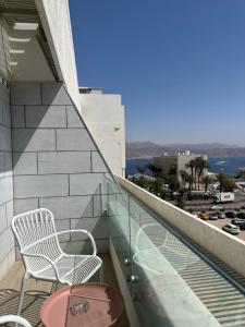 uma varanda com duas cadeiras e uma mesa num edifício em Nathan's Suites On The Beach em Eilat