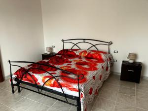 a bedroom with a bed with a red comforter at Casa Lubiana in Carbonia