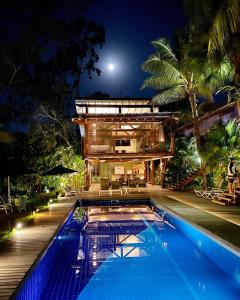 a house with a swimming pool at night at Flat Camburi in Camburi