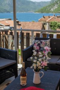 - une bouteille de vin et un vase avec des fleurs sur une table dans l'établissement Apartmani Zukic, à Risan
