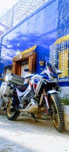 une moto garée devant un bâtiment bleu dans l'établissement Atlas Room, à Midelt