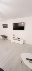 een witte woonkamer met een flatscreen-tv aan de muur bij Apartament Central in Tulcea