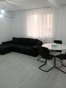 een woonkamer met een zwarte bank en een tafel bij Apartament Central in Tulcea