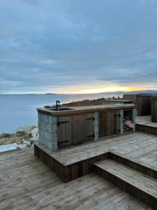 a house on a deck with a view of the water at Jacuzzi, utekjøkken og sjøutsikt i hel hytte ved sjøen in Hitra +3 photos