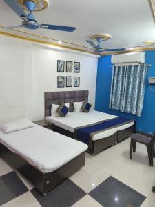a bedroom with two beds and a blue wall at Trinetra Inn in Varanasi