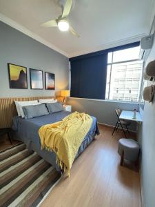 um quarto com uma cama com um cobertor amarelo em LGBT Friendly - Quarto em Ipanema Posto 9 - Casa de Vitor e Carlos no Rio de Janeiro