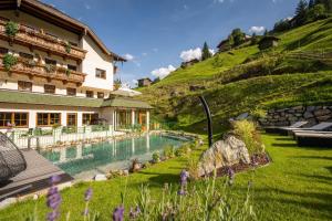un resort con piscina e collina di Naturhotel Hüttenwirt im Grossarltal a Hüttschlag