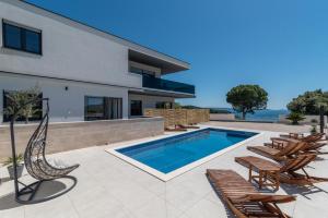 a villa with a swimming pool and chairs at Villa Helena in Trogir