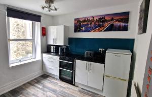 a kitchen with white cabinets and a black stove at The Penthouse NY Loft Apartment in Barmouth