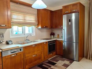 a kitchen with wooden cabinets and a stainless steel refrigerator at Eleni's Holiday Home in Kalamata
