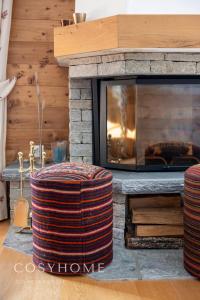 ein Wohnzimmer mit einem Kamin und 2 Hockern in der Unterkunft Le Saint Georges l Jardin et vue in Crans-Montana