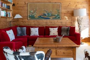 a living room with a red couch and a table at Le Saint Georges l Jardin et vue in Crans-Montana