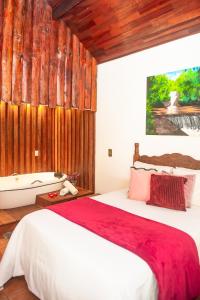 a bedroom with a large bed and wooden walls at Chalés Recanto da cachoeira in Monte Verde