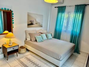 a bedroom with a bed with blue curtains and a table at Eratous Seaside House in Varnávas