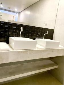 a bathroom with two sinks and a mirror at Flat Camburi in Camburi