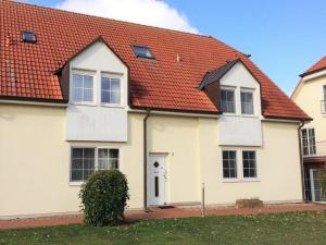 een wit huis met een oranje dak bij Pleasant apartment in Insel Poel in Insel Poel