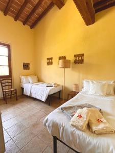 two beds in a room with yellow walls at Relais Poggio Del Melograno in Montecatini Val di Cecina