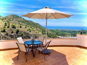 a patio with a table and chairs and an umbrella at Buenos Sueños- Balcon de Frigiliana in Frigiliana
