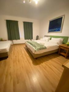 1 dormitorio con 2 camas y suelo de madera en Malom Udvar Panzió és Étterem en Bér