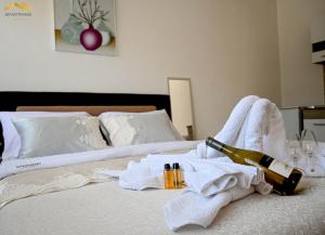 a bed with a bottle of wine and towels on it at Apartmani Jaguzovic in Mrkonjić Grad