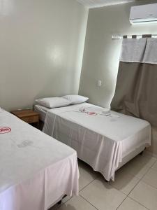 um quarto com duas camas com lençóis brancos em POUSADA E AGENCIA CLEDIO TURISMO em Barreirinhas