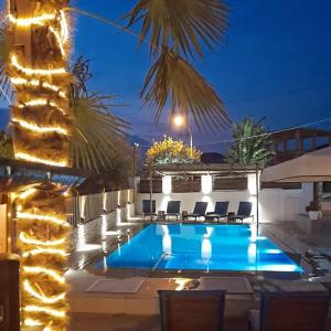 a swimming pool at night with chairs and a palm tree at Hotel Villa Ruci in Ksamil