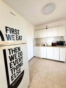 a kitchen with a first we eat sign on the wall at Amazing sea view in Qiryat Yam