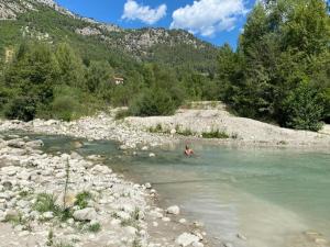 a person swimming in a river in the mountains at Chambre campagnarde in Roquestéron