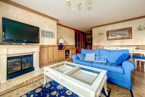 een woonkamer met een blauwe bank en een open haard bij Maison Alpina l Family l 6 pers. in Crans-Montana