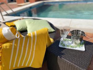 馬拉加的住宿－Hevres El Capricho，一张桌子,上面有玻璃杯,在游泳池边