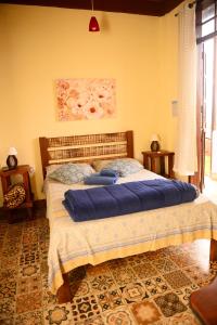 a bedroom with a large bed with blue sheets at Pousada Residência Balestra in Tiradentes
