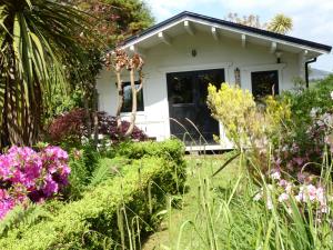 mały biały dom z kwiatami na dziedzińcu w obiekcie Rodeen w mieście Castletownbere