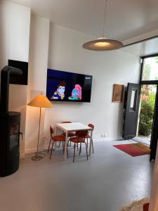 a dining room with a table and chairs and a tv at ORANGE Studio in Bois-Colombes