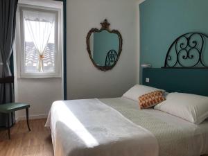 Schlafzimmer mit einem Bett, einem Spiegel und einem Fenster in der Unterkunft DIMOR'A' ROOMS in Pitigliano