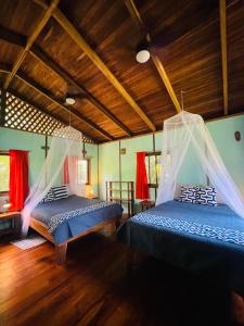 two beds in a room with wooden ceilings and red curtains at Cabinas Yamann in Manzanillo