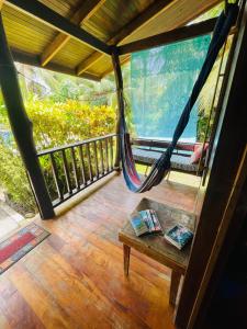 a porch with a hammock and a table on a balcony at Cabinas Yamann in Manzanillo