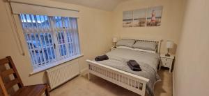 a small bedroom with a bed and two windows at Two bedroom character cottage in Rhuddlan