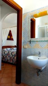 La salle de bains est pourvue d'un lavabo, d'un miroir et d'un lit. dans l'établissement Villa Agnese, à Badesi